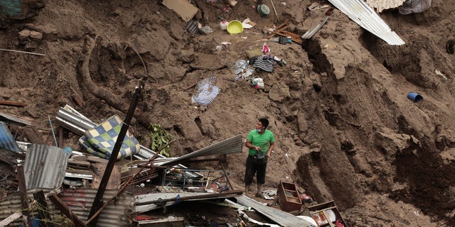 A man seeks to salvage some of his belongings from what used to be his home, destroyed by the waters of the Acelhuate River, in the New Israel Community of San Salvador, El Salvador, Sunday, May 31, 2020.