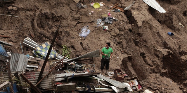 A man seeks to salvage some of his belongings from what used to be his home, destroyed by the waters of the Acelhuate River, in the New Israel Community of San Salvador, El Salvador, Sunday, May 31, 2020.