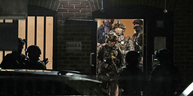 Armed police officers work at a block of flats off Basingstoke Road in Reading after an incident at Forbury Gardens park in the town center of Reading, England, early Sunday. (Steve Parsons/PA via AP)