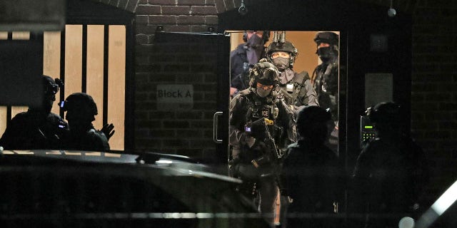 Armed police officers work at a block of flats off Basingstoke Road in Reading after an incident at Forbury Gardens park in the town center of Reading, England, early Sunday. (Steve Parsons/PA via AP)