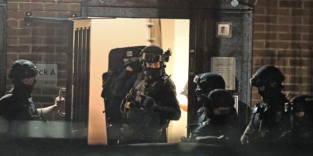 Armed police officers work at a block of flats off Basingstoke Road in Reading after an incident at Forbury Gardens park in Reading, England, Saturday, June 20, 2020. Several people were injured in a stabbing attack on Saturday, and British media said police were treating it as “terrorism-related.” (Steve Parsons/PA via AP)