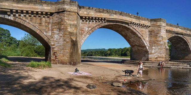 A family play in the shallows on the banks of the river Tyne, that has very low water levels, at Corbridge, England, June 1.