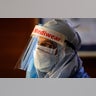 A health worker in a protective suit listens to people standing in a queue for COVID 19 tests at Sir Ganga Ram hospital in New Delhi, India, June 16, 2020.