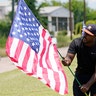 Bryan Smart planting American flags along Hillcroft Ave. as he walks toward The Fountain of Praise church in Houston.