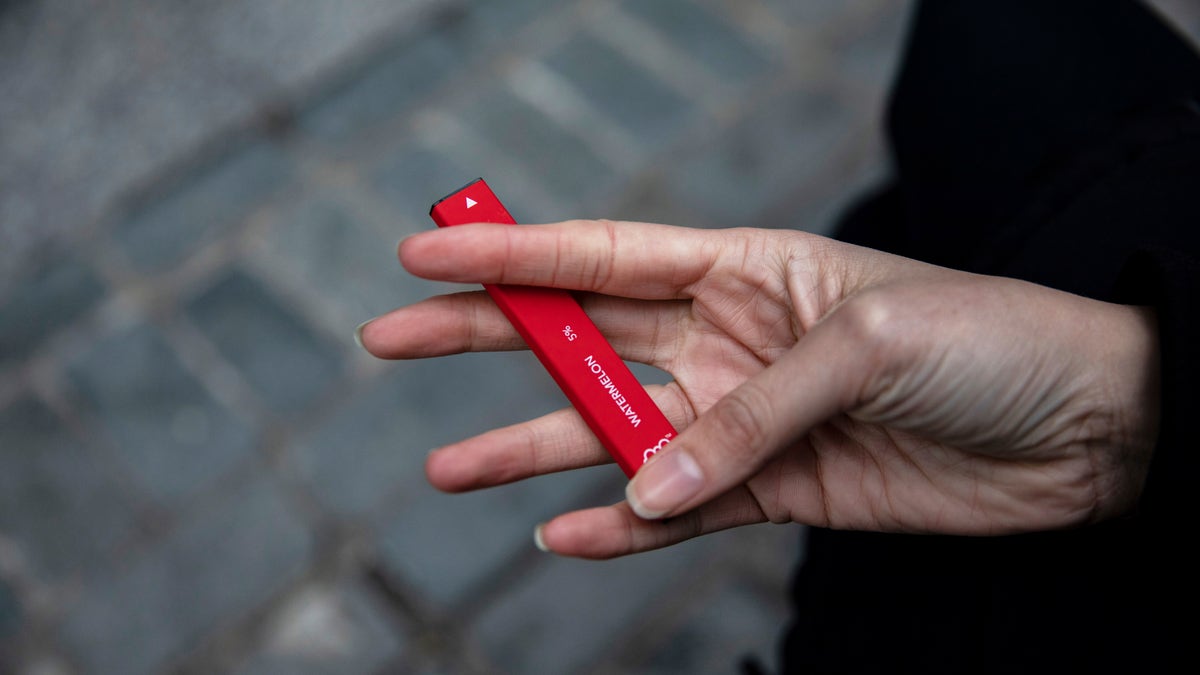 In this Jan. 31, 2020 file photo a woman holds a Puff Bar flavored disposable vape device in New York. U.S. health officials are cracking down on the brand of fruity disposable e-cigarettes that is popular with teenagers, saying the company never had permission to launch in the U.S. The Food and Drug Administration sent a letter Monday, July 20 telling the maker of Puff Bar e-cigarettes to remove its products from the market, including flavors like Mango, Pink Lemonade and Strawberry.