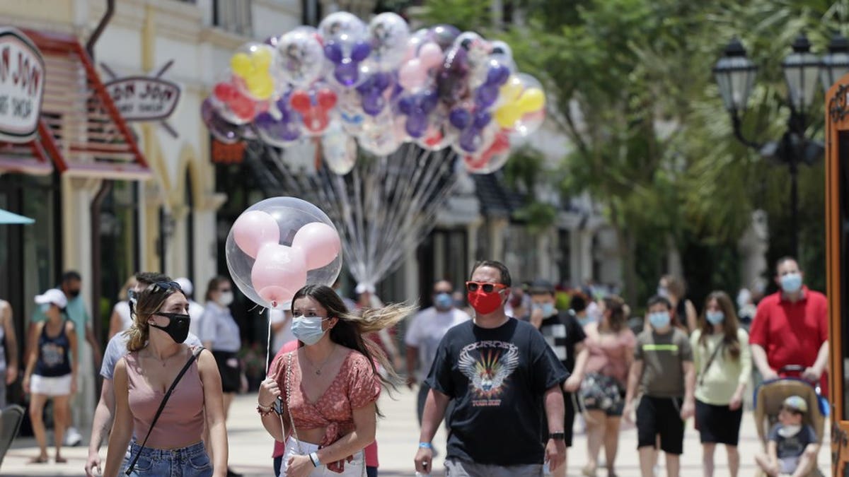 In this June 16, 2020, file photo, guests required to wear masks because of the coronavirus stroll through the Disney Springs shopping, dining and entertainment complex in Lake Buena Vista, Fla. Magic Kingdom and Animal Kingdom will reopen on July 11. In May, the company opened Disney Springs.