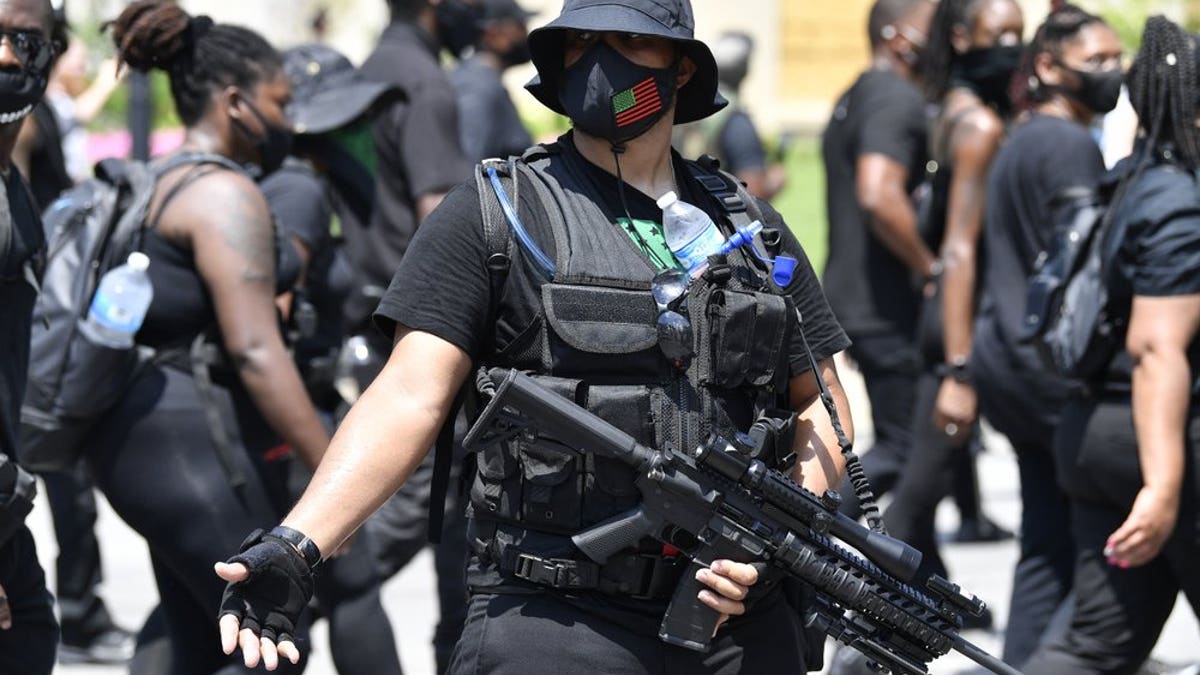 An armed member of the "NFAC" scans the crowd during a march through downtown toward the Hall of Justice in Louisville, Ky., Saturday, July 25, 2020. Hundreds of activists demanded justice for Breonna Taylor during the demonstrations in her hometown that drew counter-protesters from a white militia group. Taylor, a 26-year-old EMT, was fatally shot when police officers burst into her Louisville apartment using a no-knock warrant during an investigation.(AP Photo/Timothy D. Easley)