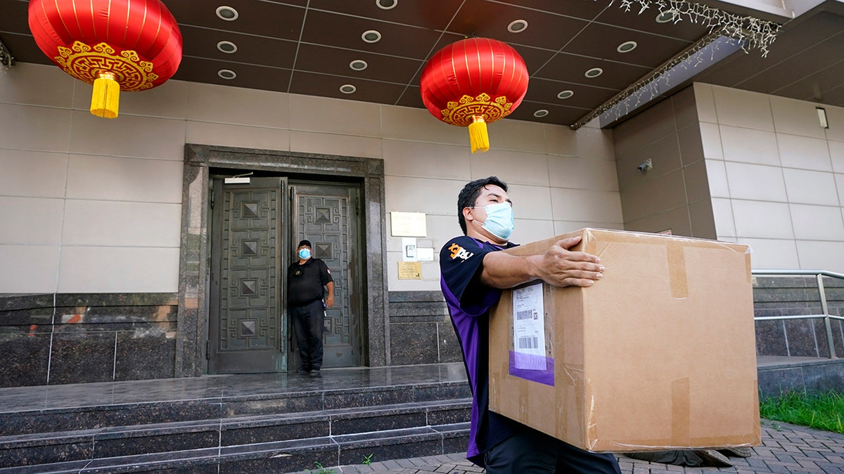 A FedEx employee removes a box from the Chinese Consulate Thursday, July 23, 2020, in Houston. (AP Photo/David J. Phillip)