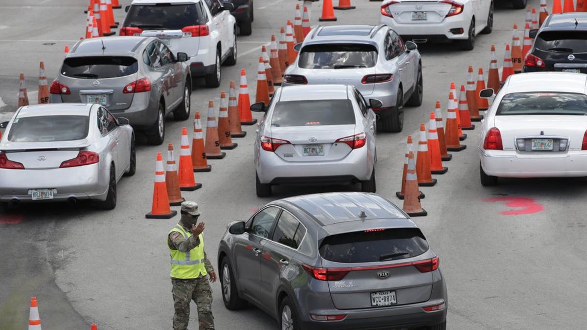 A National Guardsman directs traffic at a COVID-19 testing site outside Hard Rock Stadium, Wednesday, July 8, 2020, in Miami Gardens, Fla. Florida is one of the nation's hot spots for coronavirus.