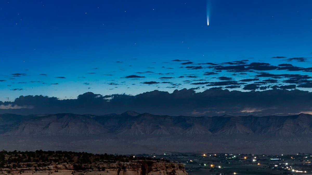 Comet Neowise soars in the horizon of the early morning sky seen from near the grand view lookout at the Colorado National Monument west of Grand Junction, Colo., Thursday, July 9, 2020. The newly discovered comet is streaking past Earth, providing a celestial nighttime show after buzzing the sun and expanding its tail. (Conrad Earnest via AP)