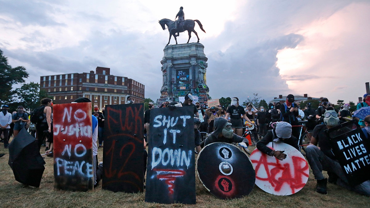 Protesters with shields and gas masks wait for police action as they surround the statue of Confederate Gen. Robert E. Lee on Monument Avenue, Tuesday June 23, 2020, in Richmond, Virginia. (AP Photo/Steve Helber)