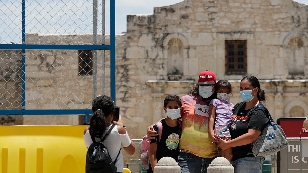 Visitors wearing masks to protect against the spread of COVID-19 pose for photos at the Alamo, which remains closed, in San Antonio last month. Cases of COVID-19 have spiked in Texas to over 200,000, according to government figures. (AP Photo/Eric Gay)