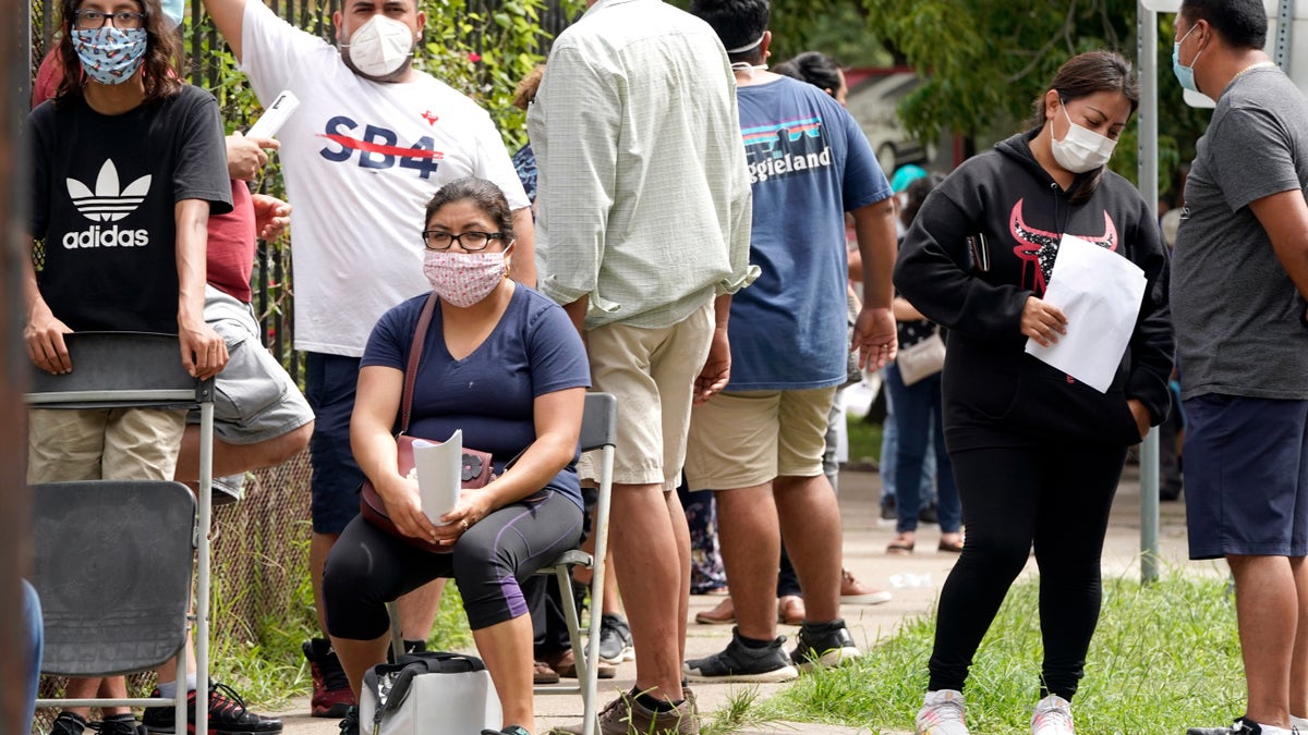 People wait in line at a free COVID-19 testing site provided by United Memorial Medical Center, at the Mexican Consulate, Sunday, June 28, 2020, in Houston. Confirmed cases of the coronavirus in Texas continue to surge. Texas Gov. Greg Abbott, on Friday, shut down bars again and scaled back restaurant dining as cases climbed to record levels after the state embarked on one of America's fastest reopenings. (AP Photo/David J. Phillip)