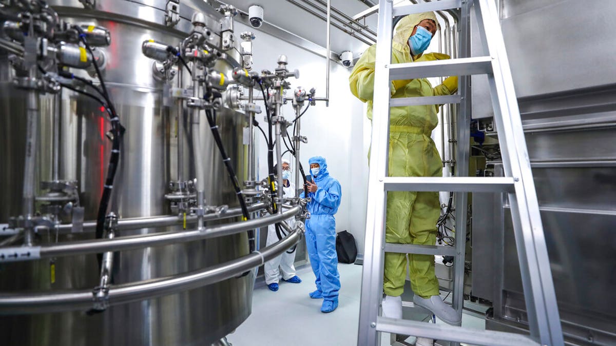 Staff members check and clean equipment at a vaccine production plant operated by SinoPharm in Beijing. (Zhang Yuwei/Xinhua via AP)