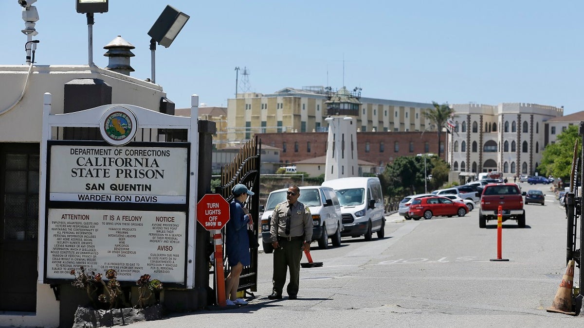 A Department of Corrections officer guards the main entryway leading into San Quentin State Prison in San Quentin, Calif. Corrections officials said Friday that up to 8,000 state prison inmates could be released in an effort to prevent the spread of the coronavirus in correctional facilities. (AP Photo/Eric Risberg, File)