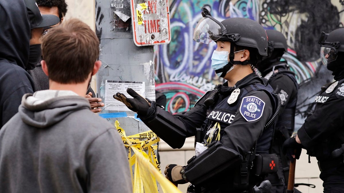 A police officer engages with a protester last week in Seattle, where streets had been blocked off in an area demonstrators had occupied for weeks. (AP Photo/Elaine Thompson)