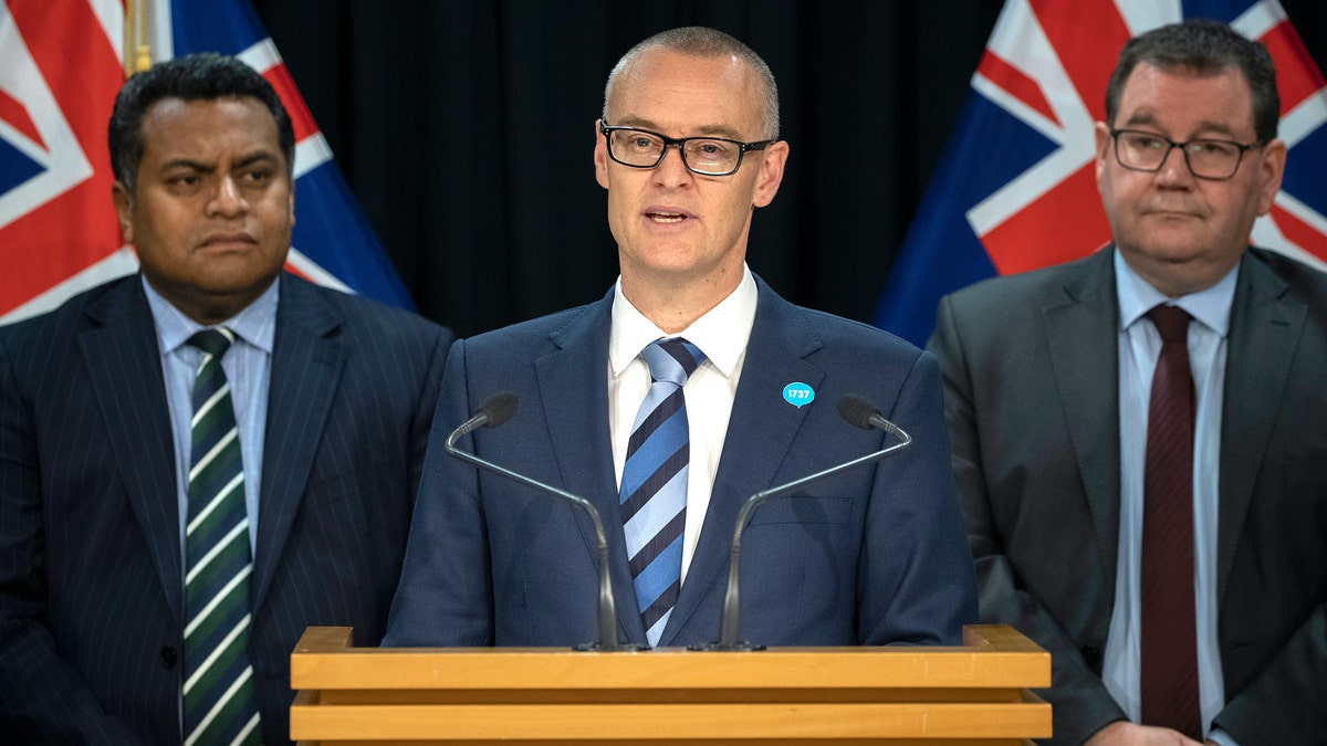 New Zealand Health Minister David Clark, center, flanked by Cabinet colleagues Grant Robertson, right, and Kris Faafoi addresses a press conference where he announced his resignation as Health Minister at parliament in Wellington, New Zealand, Thursday, July 2, 2020. (Mark Mitchell/New Zealand Herald via AP)