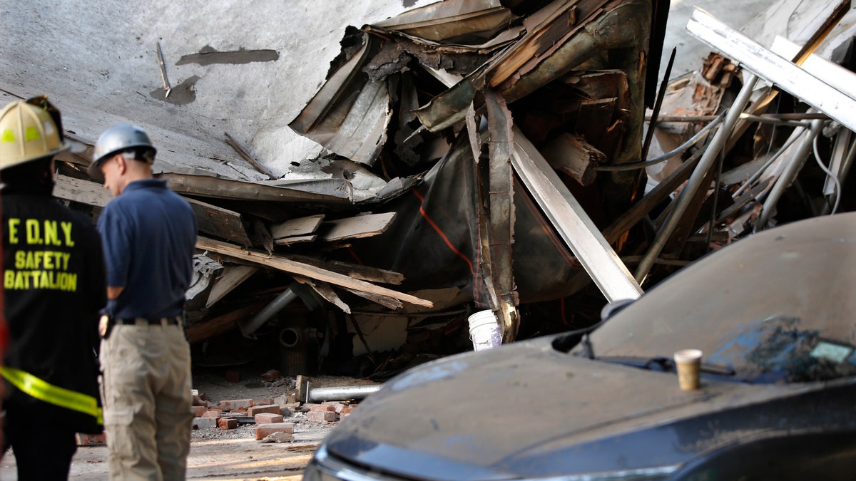 Officials standing near the rubble of the collapsed building.