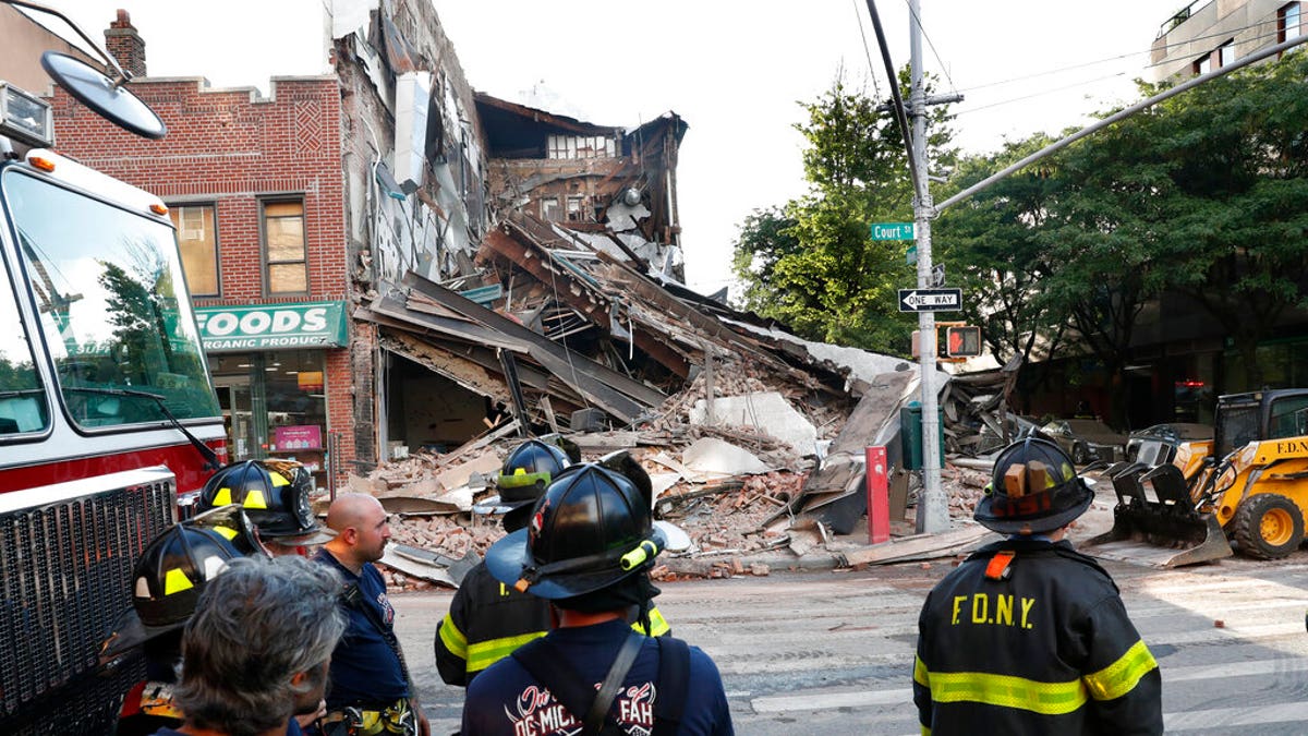 Firefighters standing near the collapsed multistory building in the Carroll Gardens neighborhood of the Brooklyn, N.Y.