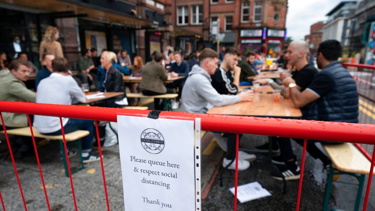 Members of the public are seen at a bar in Manchester's Northern Quarter, England, Saturday July 4, 2020. England is embarking on perhaps its biggest lockdown easing yet as pubs and restaurants have the right to reopen for the first time in more than three months Saturday. (AP Photo/Jon Super)