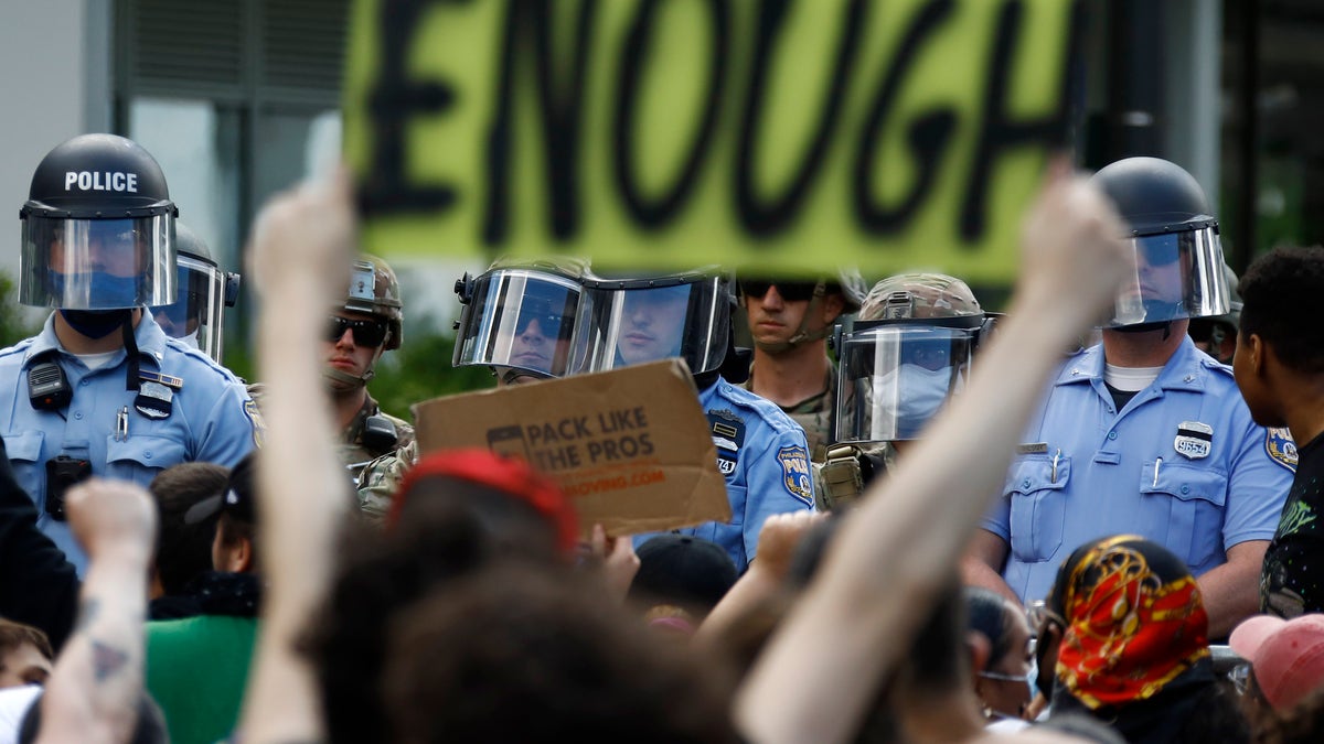 In this June 1, 2020, file photo, protesters rally as Philadelphia Police officers and Pennsylvania National Guard soldiers look on in Philadelphia, over the death of George Floyd, a black man who was in police custody in Minneapolis. Still reeling from the coronavirus pandemic and street protests over the police killing of Floyd, exhausted cities around the nation are facing yet another challenge: A surge in recent shootings has left dozens dead, including young children. (AP Photo/Matt Slocum)