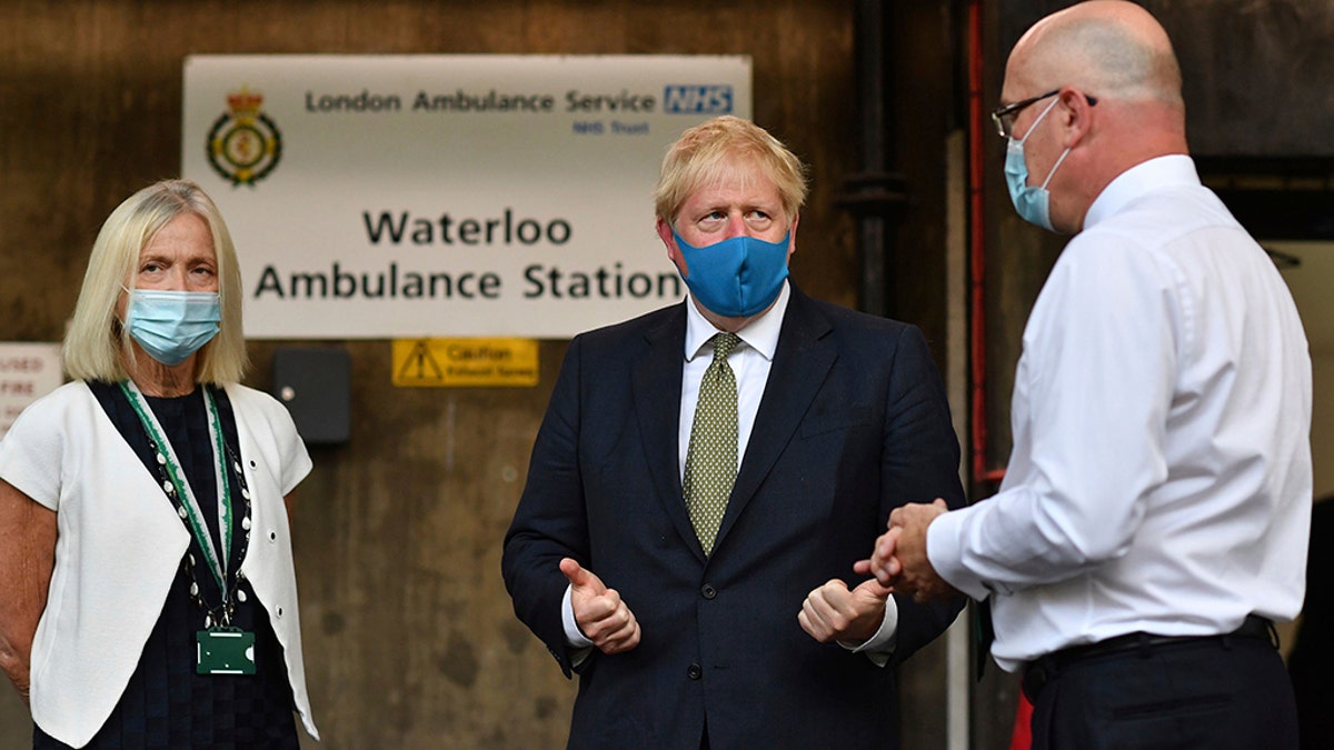 Britain's Prime Minister Boris Johnson, wearing a face mask, talks with CEO of the London Ambulance Service Garrett Emmerson, right, and Chair of the London Ambulance Service Heather Lawrence during a visit to the headquarters of the London Ambulance Service NHS Trust in London on Monday. (Ben Stansall/Pool via AP)