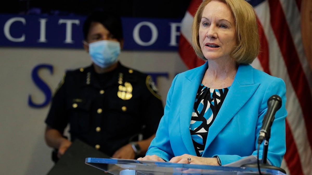 Seattle Mayor Jenny Durkan speaks at a press conference behind podium while speaking about efforts to defund the police.