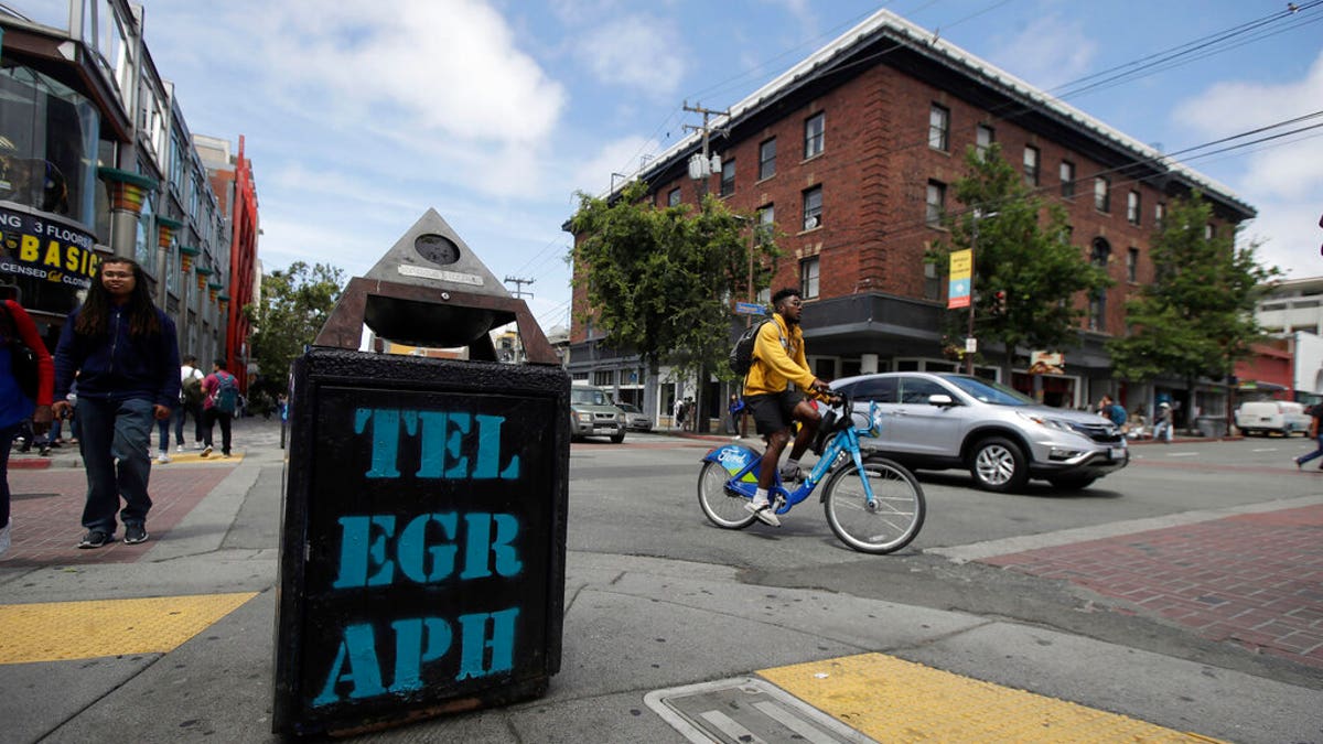 FILE - In this July 18, 2019, file photo, traffic and pedestrians cross Telegraph Avenue in Berkeley, Calif. The politically liberal city of Berkeley in Northern California is considering a proposal to shift traffic enforcement from armed police to unarmed city workers. (AP Photo/Jeff Chiu, File)