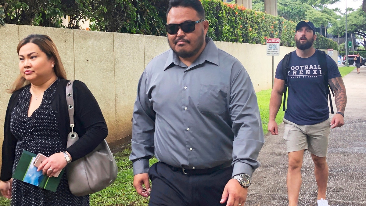 Former Honolulu police officer Reginald Ramones, center, walks down a street in Honolulu, on Sept. 25, 2019. (AP Photo/Jennifer Sinco Kelleher, File)