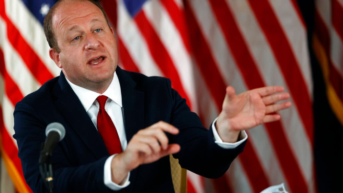 FILE: Colorado Governor Jared Polis makes a point during a news conference on the state's efforts to contain the spread of the new coronavirus in Denver.