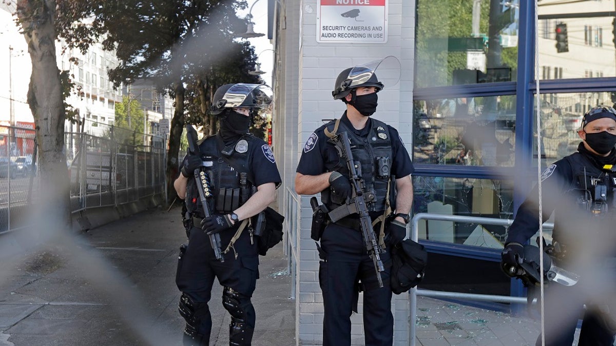 Seattle police officers hold weapons as they stand guard outside the East Precinct Building recently. (Associated Press)