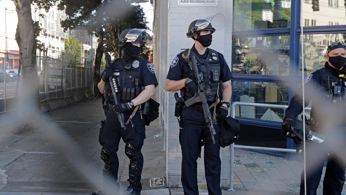 Seattle police officers hold weapons as they stand guard outside the East Precinct Building recently. (Associated Press)