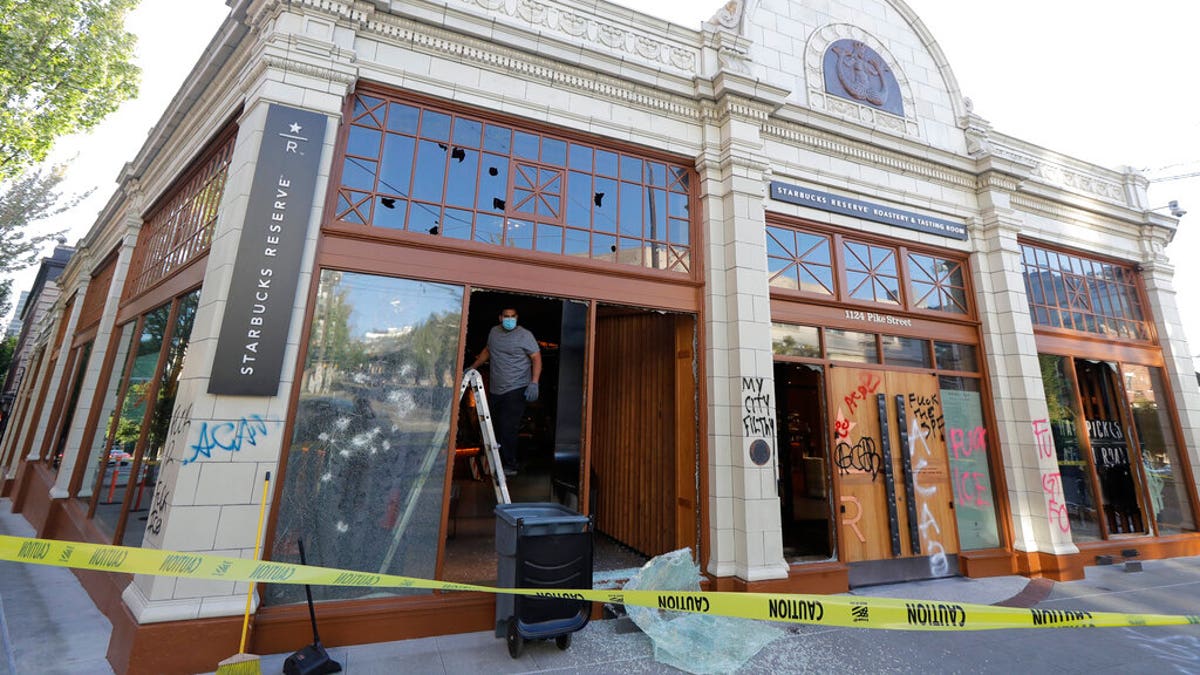 A worker clears glass from broken windows at the Starbucks Roastery, Sunday, July 19, 2020 in Seattle's Capitol Hill neighborhood. Protesters broke windows at the store earlier in the afternoon. (AP Photo/Ted S. Warren)