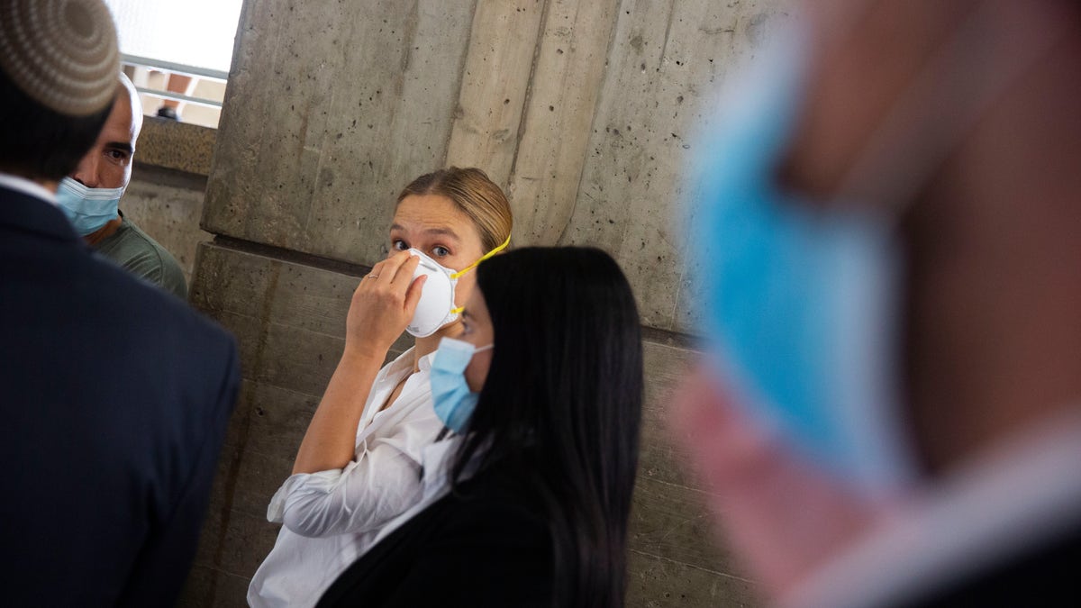 Israeli top model Bar Refaeli, center, wearing a face mask arrives to a court along with lawyers, in Tel Aviv, Israel, Monday, July 20, 2020. (AP Photo/Oded Balilty, Pool)