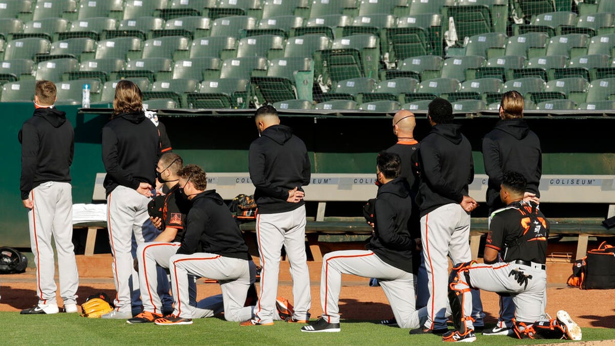 Some San Francisco Giants kneel during the national anthem prior to an exhibition baseball game against the Oakland Athletics on Monday, July 20, 2020, in Oakland, Calif. (AP Photo/Ben Margot)
