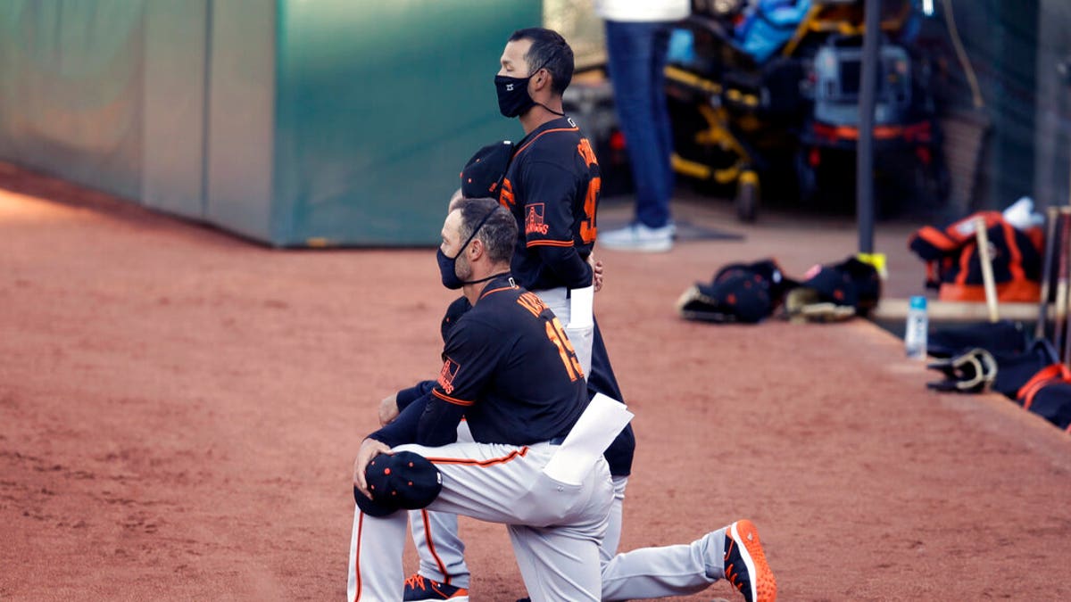 San Francisco Giants' manager Gabe Kapler kneels during the national anthem prior to an exhibition baseball game against the Oakland Athletics, Monday, July 20, 2020, in Oakland, Calif.