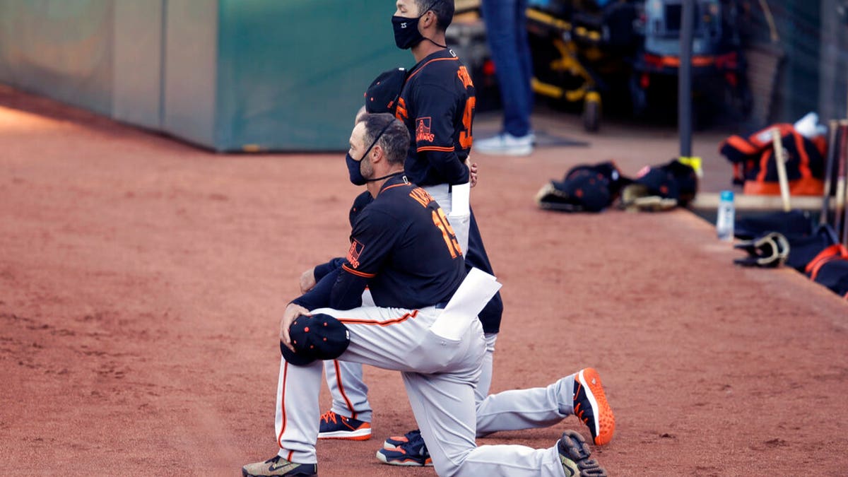 San Francisco Giants' manager Gabe Kapler kneels during the national anthem prior to an exhibition baseball game against the Oakland Athletics, Monday, July 20, 2020, in Oakland, Calif.