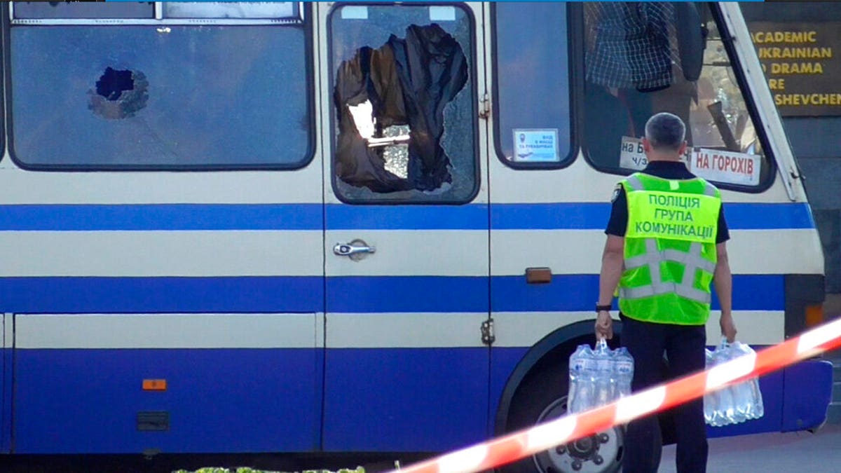 A policeman brings water for hostages contained in a bus after an armed man seized the long-distance bus and took 13 people hostage in Lutsk.