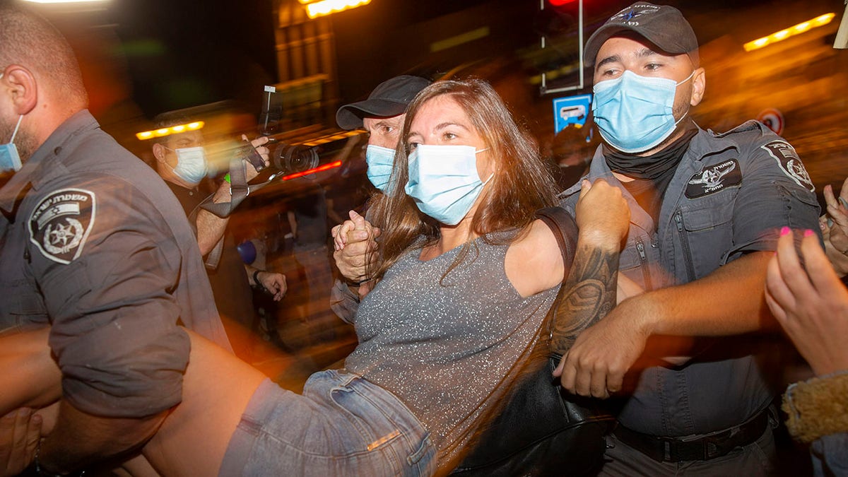 Israeli police officers arrest a demonstrator during a protest against Israel's Prime Minister Benjamin Netanyahu outside his residence in Jerusalem, early Friday, July 24, 2020. (Associated Press)