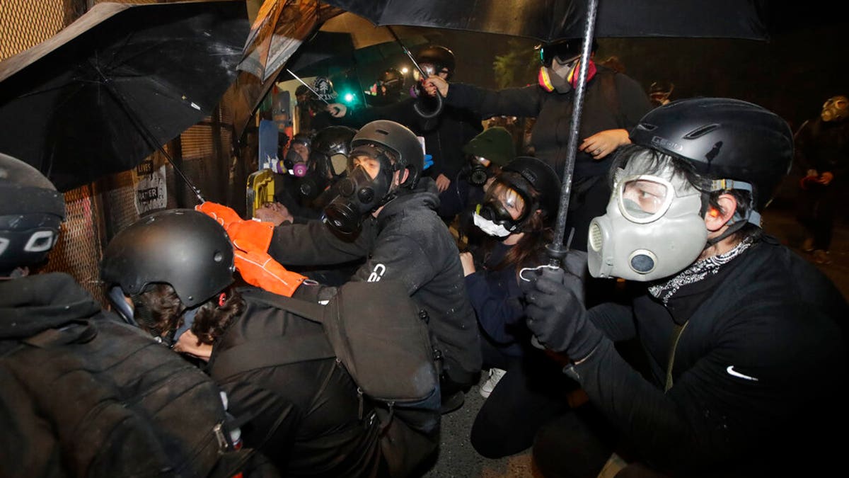 Demonstrators shield themselves from tear gas launched over a fence by federal officers during a Black Lives Matter protest at the Mark O. Hatfield United States Courthouse Friday, July 24, 2020, in Portland, Ore.?