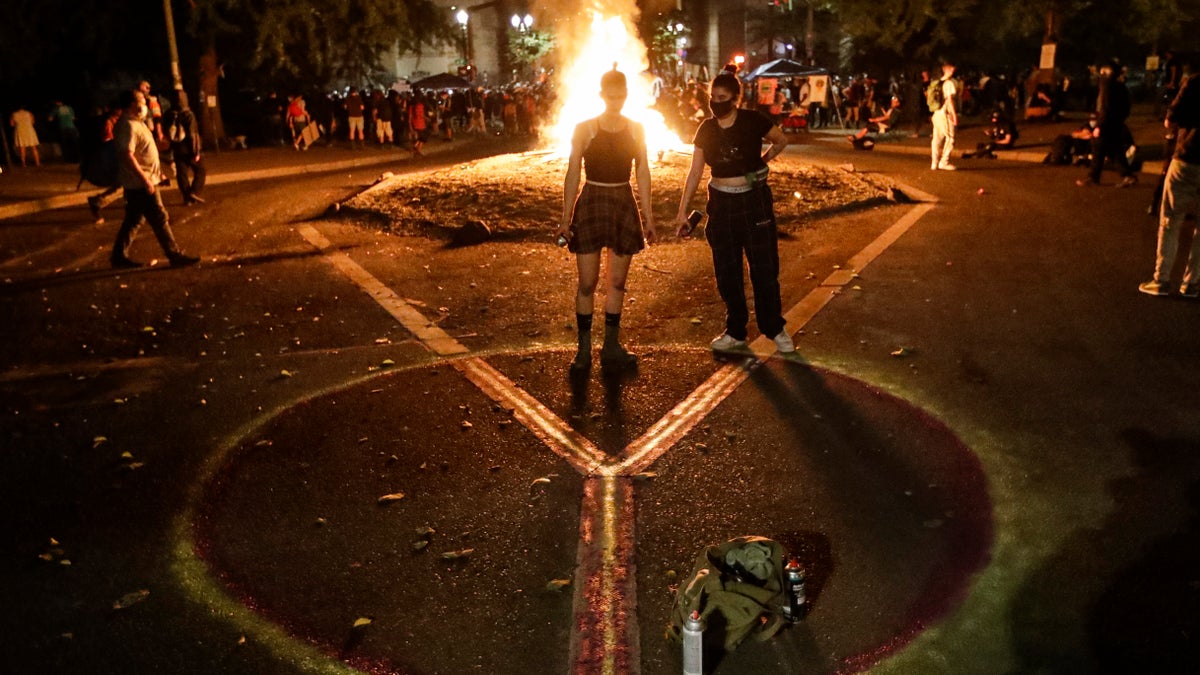 Demonstrators draw a peace sign in front of a fire during a Black Lives Matter protest at the Mark O. Hatfield United States Courthouse Tuesday, July 28, 2020, in Portland, Ore.