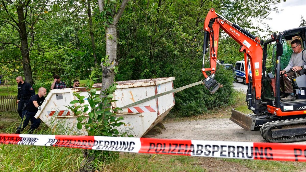 Germany police officers remove a container during a search at an allotment garden plot in Seelze, near Hannover, Germany, Wednesday, July 29, 2020. Police have begun searching an allotment garden plot, believed to be in connection with the 2007 Portugal disappearance of missing British girl Madeleine McCann. (AP Photo/Martin Meissner)