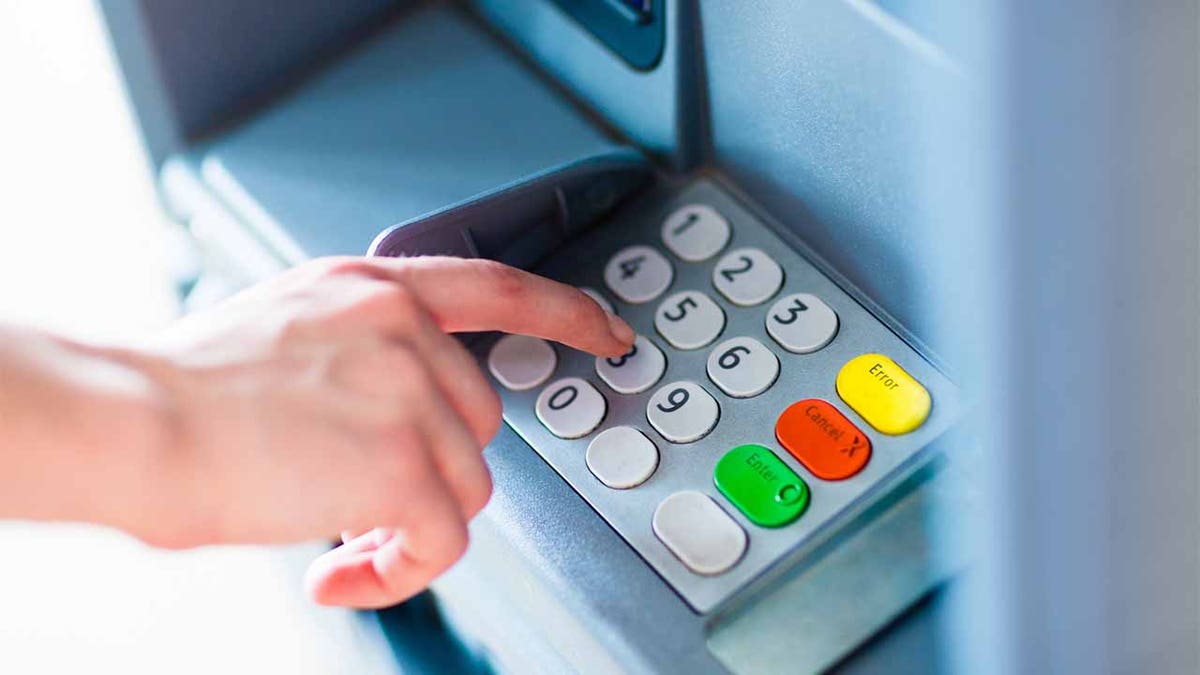 Close-up of hand entering PIN/pass code for a money transfer, on a ATM/bank machine keypad - file photo.