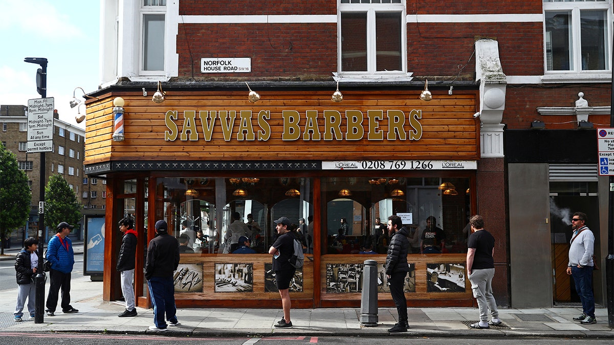 People queue outside Savvas Barbers as it reopened following the outbreak of the coronavirus disease (COVID-19), in London, Britain July 4, 2020. REUTERS/Hannah McKay - RC28MH94GQPU