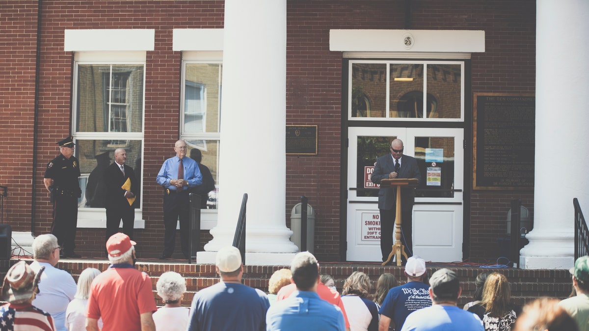 Pastor Perry Cleek speaks during an Independence Day ceremony honoring local law enforcement at the Washington County Court House in Jonesborough, Tenn., on July 4, 2020. Public Safety Director Craig Ford; Rodney Metcalf, chairman of the deacons at Lighthouse Missionary Baptist Church; and Police Chief Ron Street are pictured on the left.