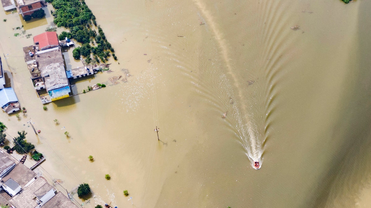 In this aerial photo released by Xinhua News Agency, rescue workers on a raft are seen moving through flood waters to help evacuate trapped residents in Sanjiao Township of Yongxiu County in central eastern China's Jiangxi Province on Monday, July 13, 2020.