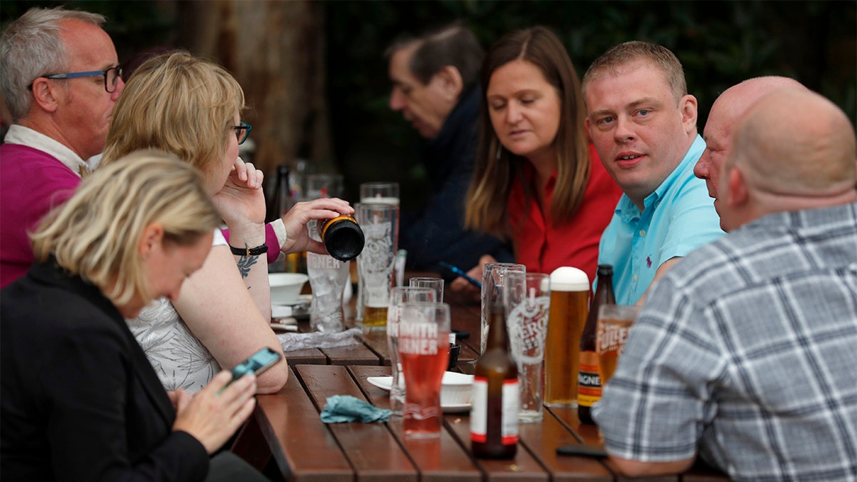 People enjoy their drinks at the beer garden of the Forester pub in London, Saturday, July 4, 2020. England is embarking on perhaps its biggest lockdown easing yet as pubs and restaurants have the right to reopen for the first time in more than three months. In addition to the reopening of much of the hospitality sector, couples can tie the knot once again, while many of those who have had enough of their lockdown hair can finally get a trim. (AP Photo/Frank Augstein)