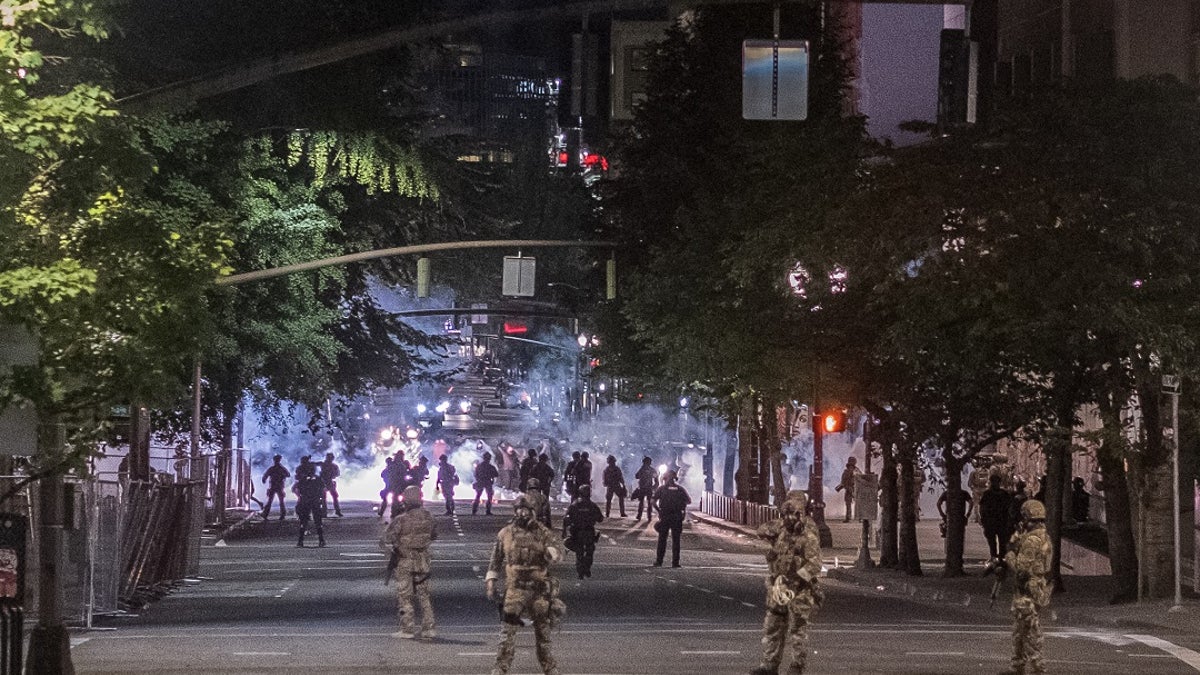 Authorities gather in the street amid protests in Portland. Ore.