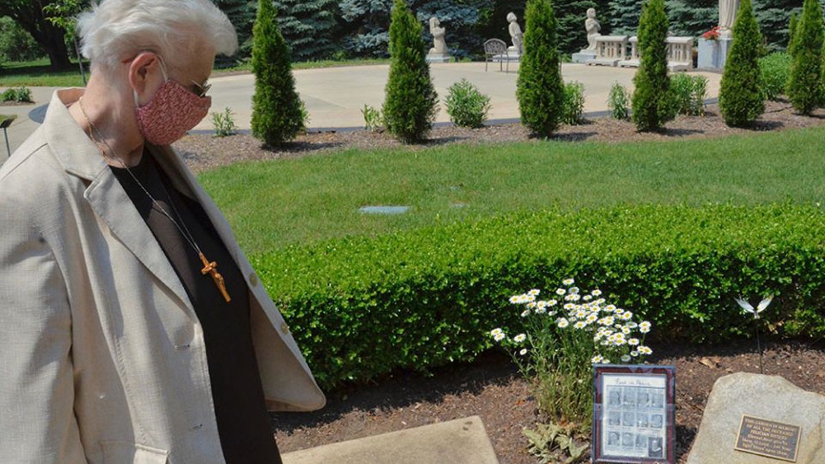 Local minister Sr. Mary Andrew Budinski looks at the memorial to remember the 12 sisters who died in one month from COVID-19 that sits in the gardens outside the Felician Sisters' convent in Livonia, Michigan.