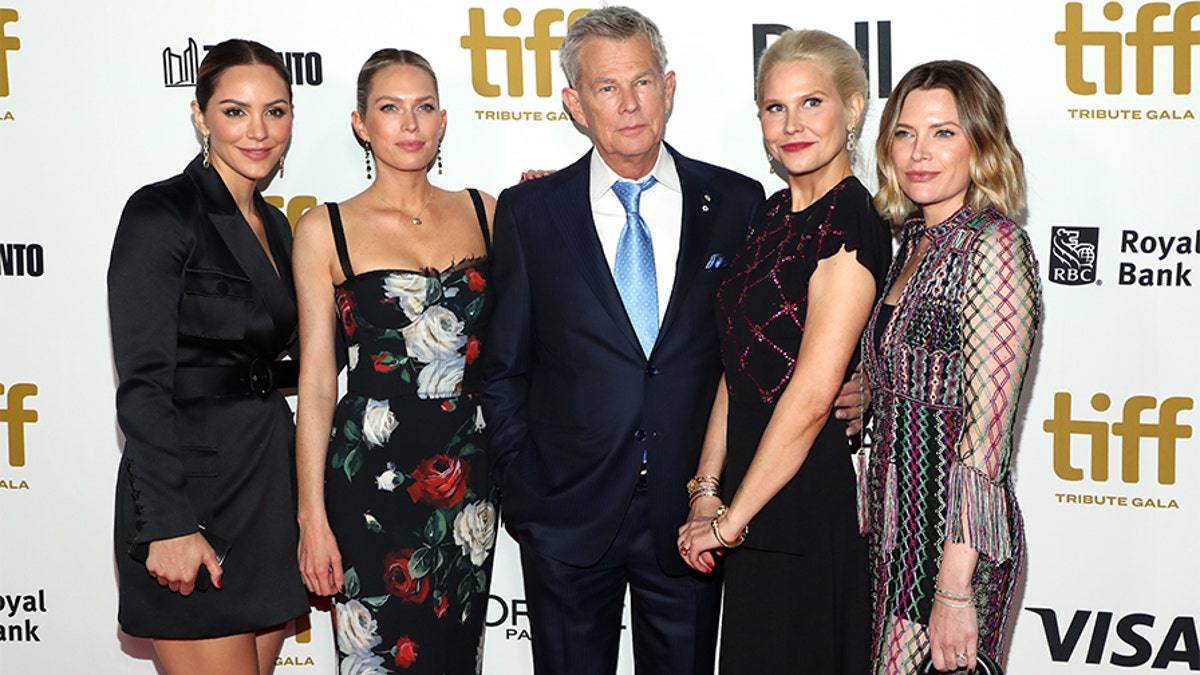 Katharine McPhee stands next to Erin Foster in a floral dress, who is next to father David Foster in a black suit and blue tie, next to Amy Foster, and Jordan Foster